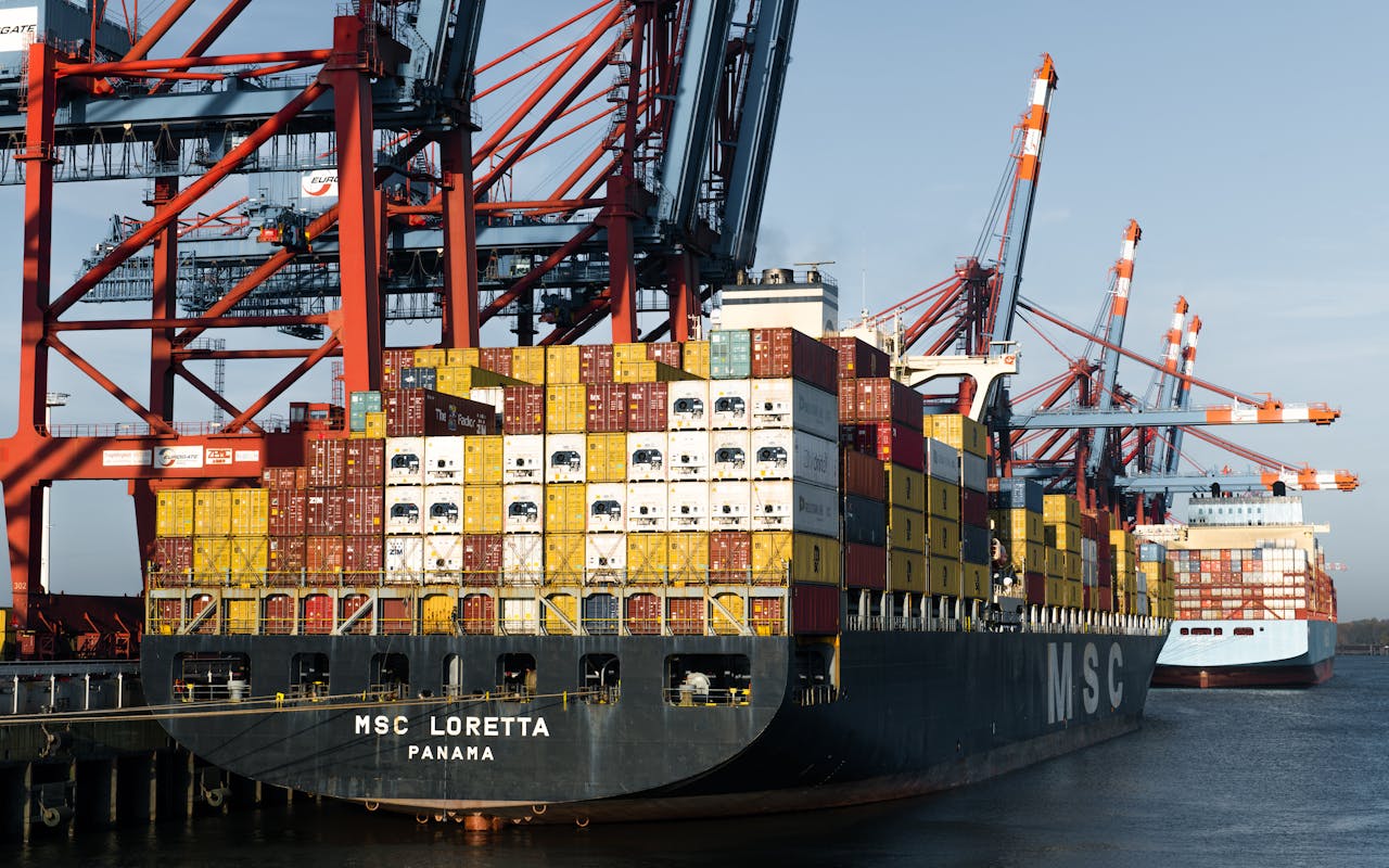 About Aerial view of cargo ships at Hamburg port terminal with cranes and shipping containers.
